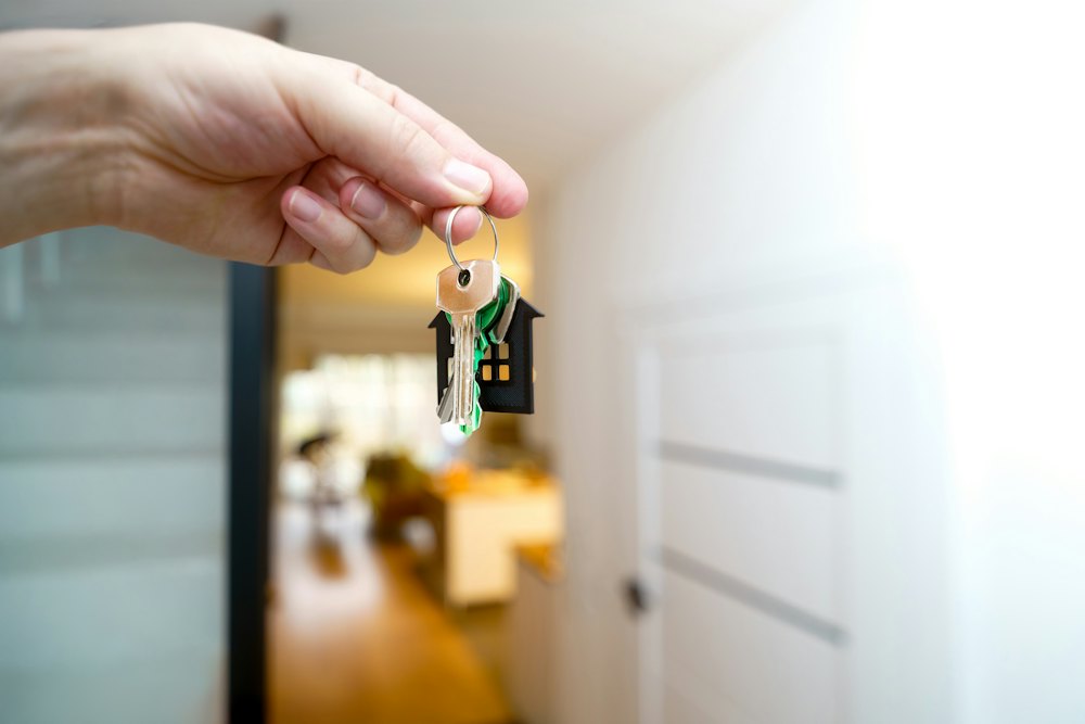 Hand holding a set of house keys in front of a front door