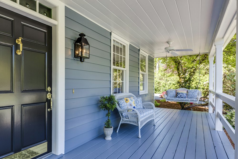Bright front porch of a home with wicker chairs
